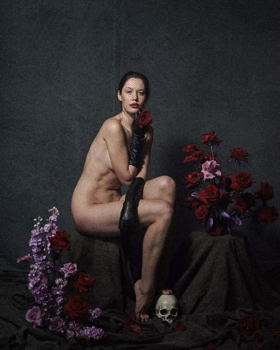 Flower installation red roses purple Matthiola stocks set design around naked girl with scull dark backdrop by Florist and set designer in Shanghai China Daria Bokova