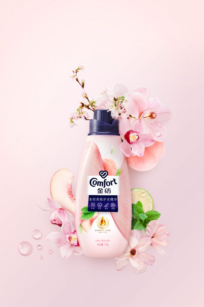 Conditioner peach bottle surrounded by cymbidium orchid flowers mint lime peach flower branches